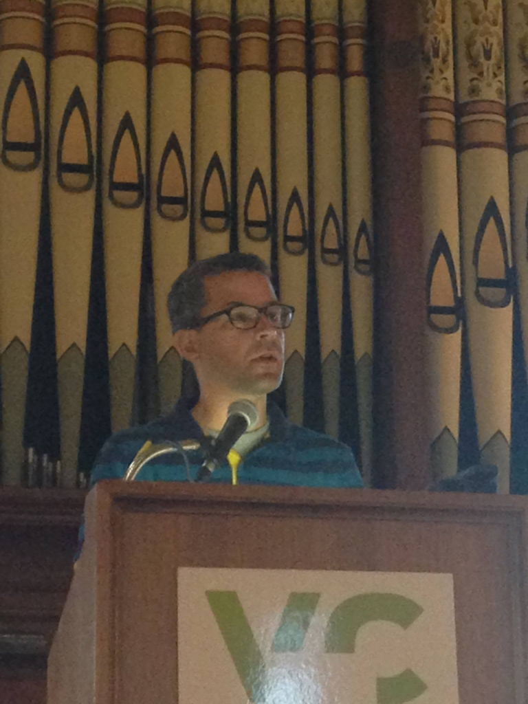 Alex giving a speech at a podium